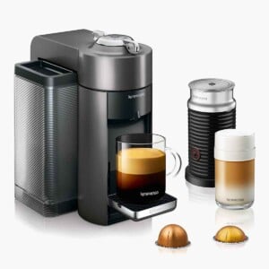 A Nespresso De'Longhi machine with two pods, and a brewed cup of espresso.