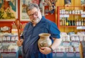 Steve Sando holding an earthenware vessel and wooden spoon.
