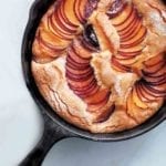 A cast-iron skillet plum cake with slices of fanned out plums baked in
