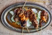 Catalan lamb skewers on sliced cucumbers topped with a romesco sauce