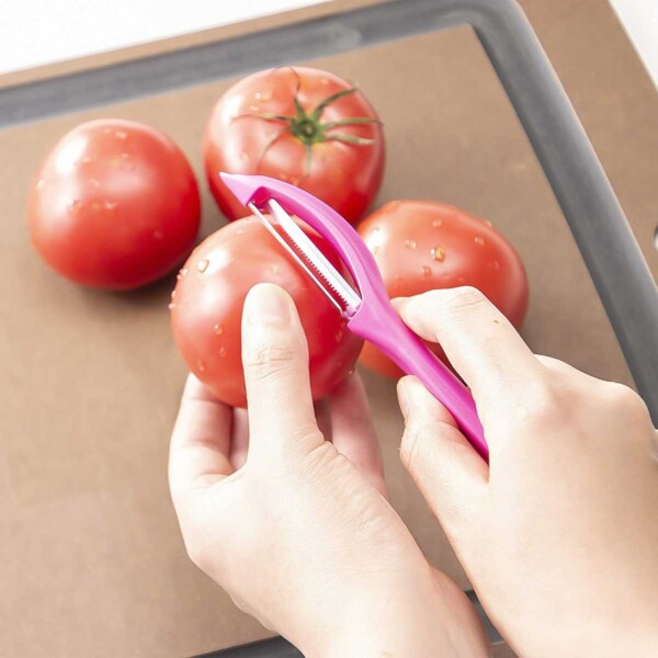 A person peeling tomatoes with a Victorinox serrated vegetable peeler.