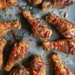 Pieces of bourbon buttermilk fried chicken on a baking sheet drizzled with honey and topped with sliced chiles.