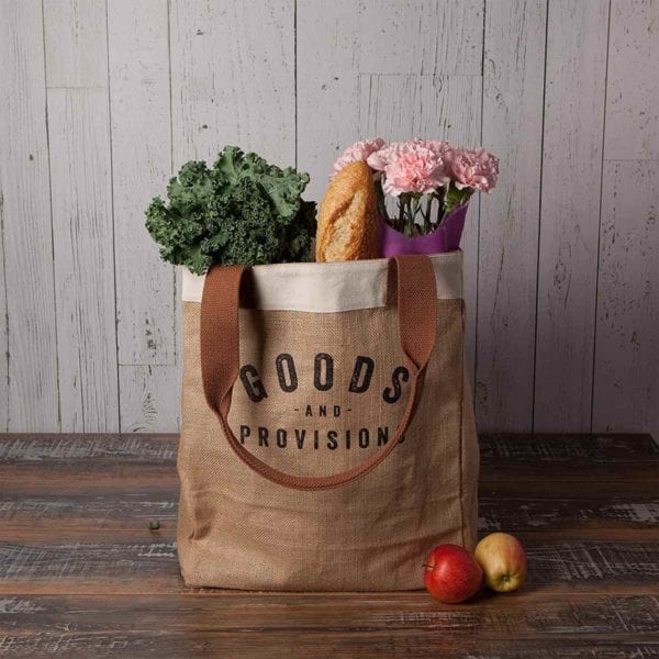 Burlap Market Tote filled with groceries on wooden table.