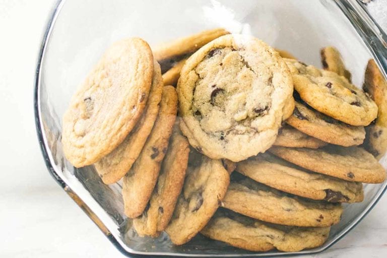 A glass jar filled with soft chocolate chip cookies.