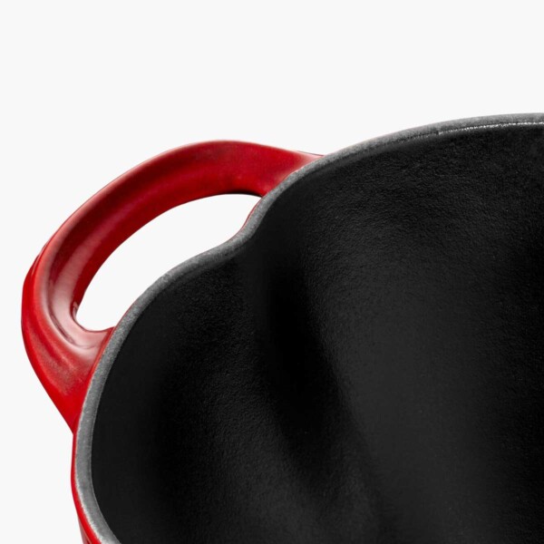 A close up shot of handle on a red Staub Cast Iron 3qt Tomato Cocotte.