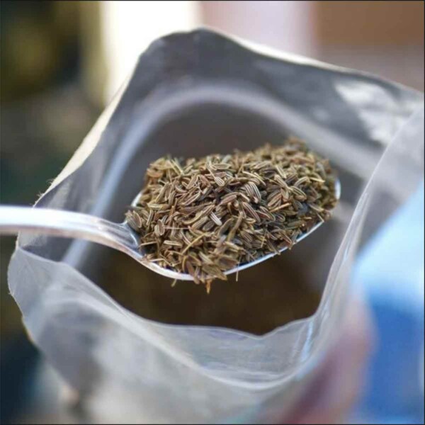 A spoonful of wild mountain cumin seeds being spooned from a bag.