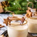 TTwo eggnogs in glasses with a gingerbread star on the lip and a rim of cinnamon.