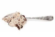 A scoop of salted peanut butter ice cream with chocolate flecks on a silver spoon.