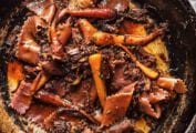 Braised beef with red wine pasta and carrots in a skillet.