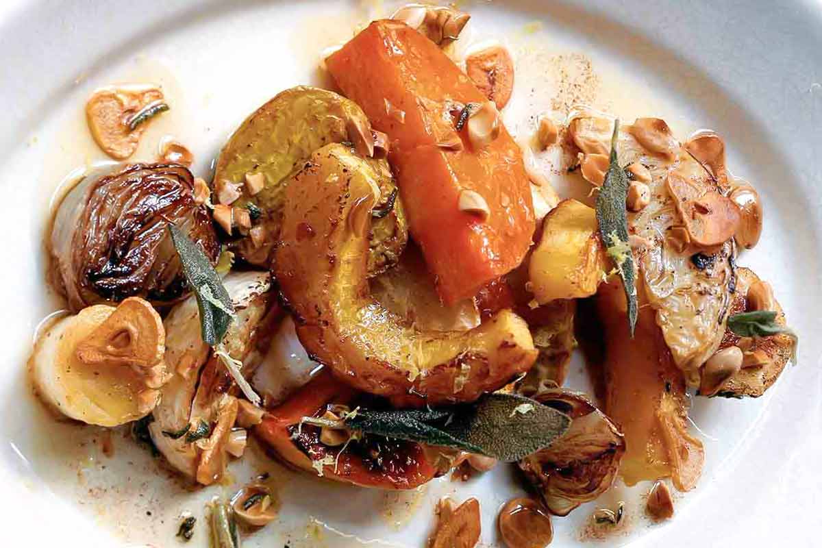 A white plate topped with roasted root vegetables and Marcona almonds.