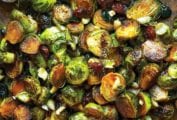 Spicy roasted Brussels sprouts with dried cranberries and macadamia nuts on a baking sheet.