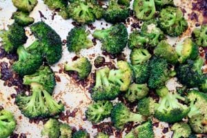 Roasted broccoli with soy sauce scattered on a baking sheet.