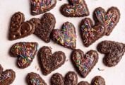 Heart shaped vegan gluten-free chocolate sugar cookies decorated with sprinkles.