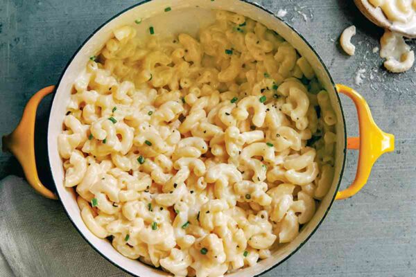 3-ingredient macaroni and cheese--elbow macaroni, cream, Cheddar cheese--in a yellow casserole with a wooden spoon.