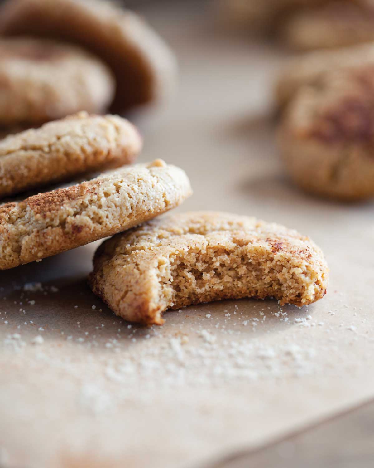 Several paleo snickerdoodles scattered on a table, one with a bite out of it.