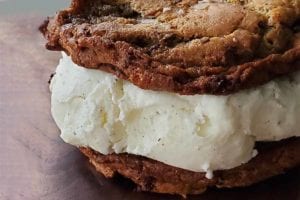 A cookie ice cream sandwich made with sourdough chocolate chip cookies and vanilla ice cream.