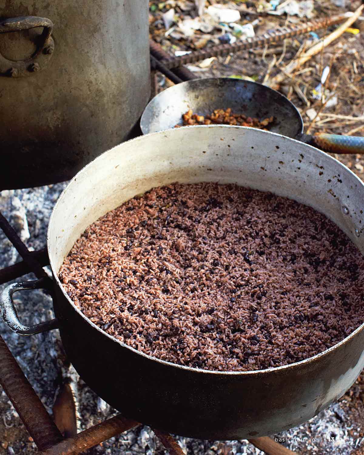 A large pot of Cuban beans and rice on a makeshift outdoor grill.