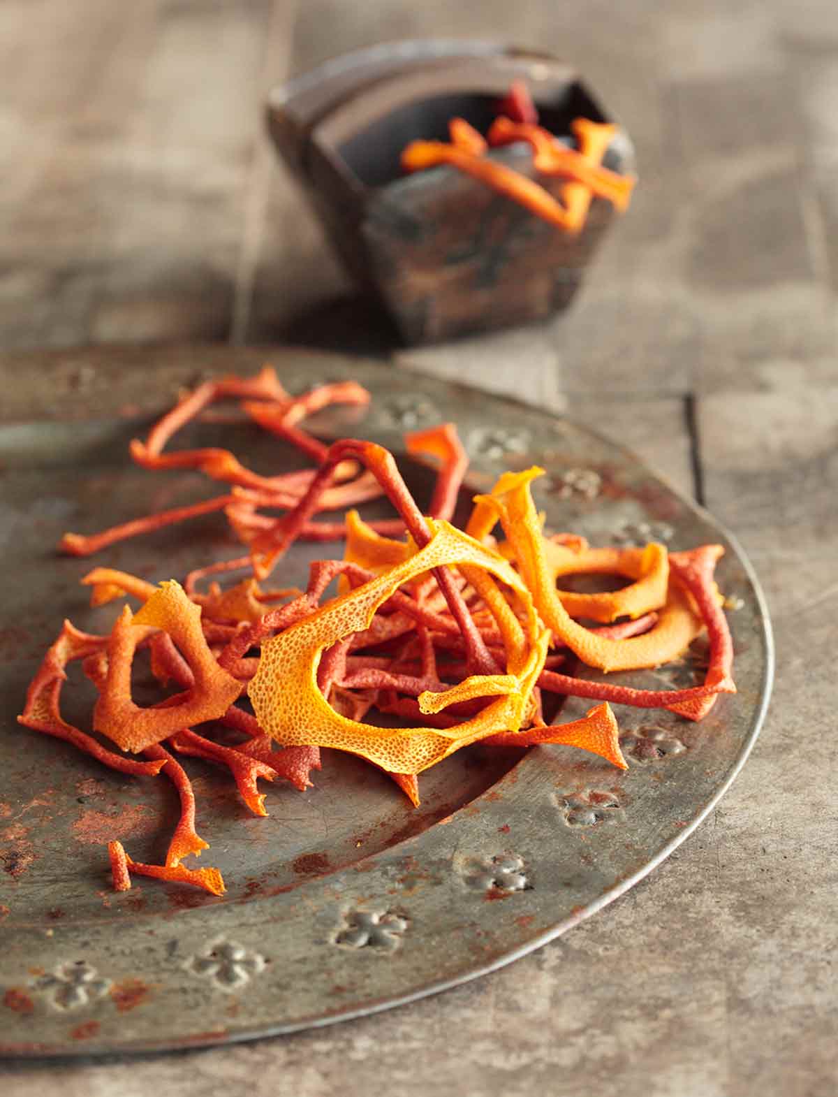 A pile of dried orange peel rings on a silver plate.