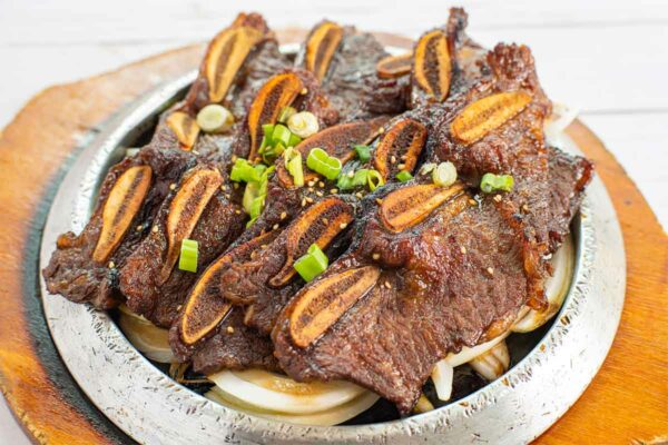 Strips of Korean beef barbecue on a platter, garnished with green onions and sesame seeds.