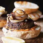 A lamb burger on half a bun topped with grilled Spanish onions.