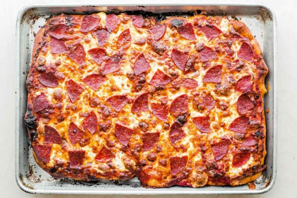 A rectangular pepperoni pan pizza on a rimmed baking sheet.