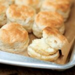 A rimmed baking sheet with rows of Southern buttermilk biscuits.