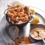 A basket of spiced shrimp with paprika mayonnaise on the side.