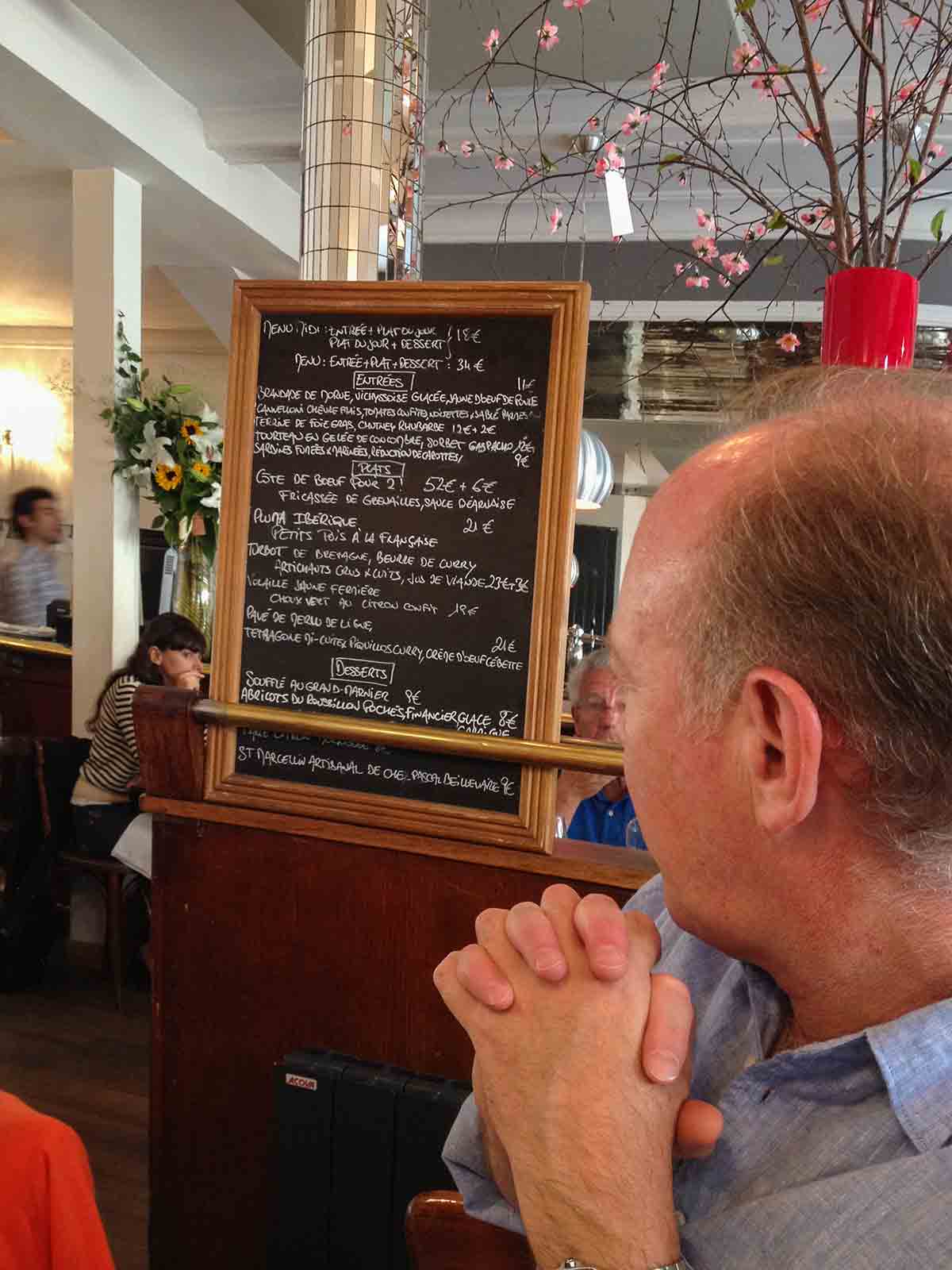 The One looking at a menu board in a cafe.