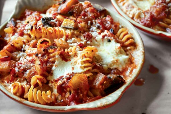Three round casserole dishes filled with baked pasta with tomatoes and eggplant.