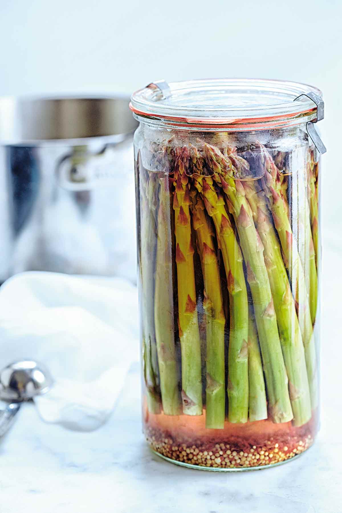 A tall canning jar filled with pickled asparagus.