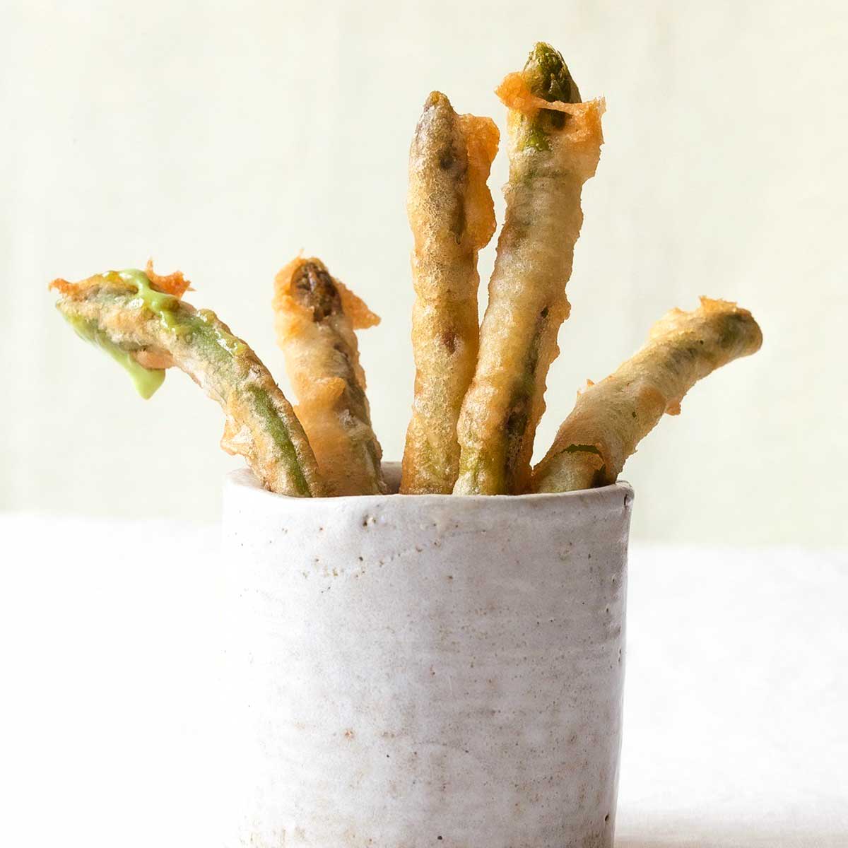 Five Portuguese deep-fried green beans standing in a white cup.