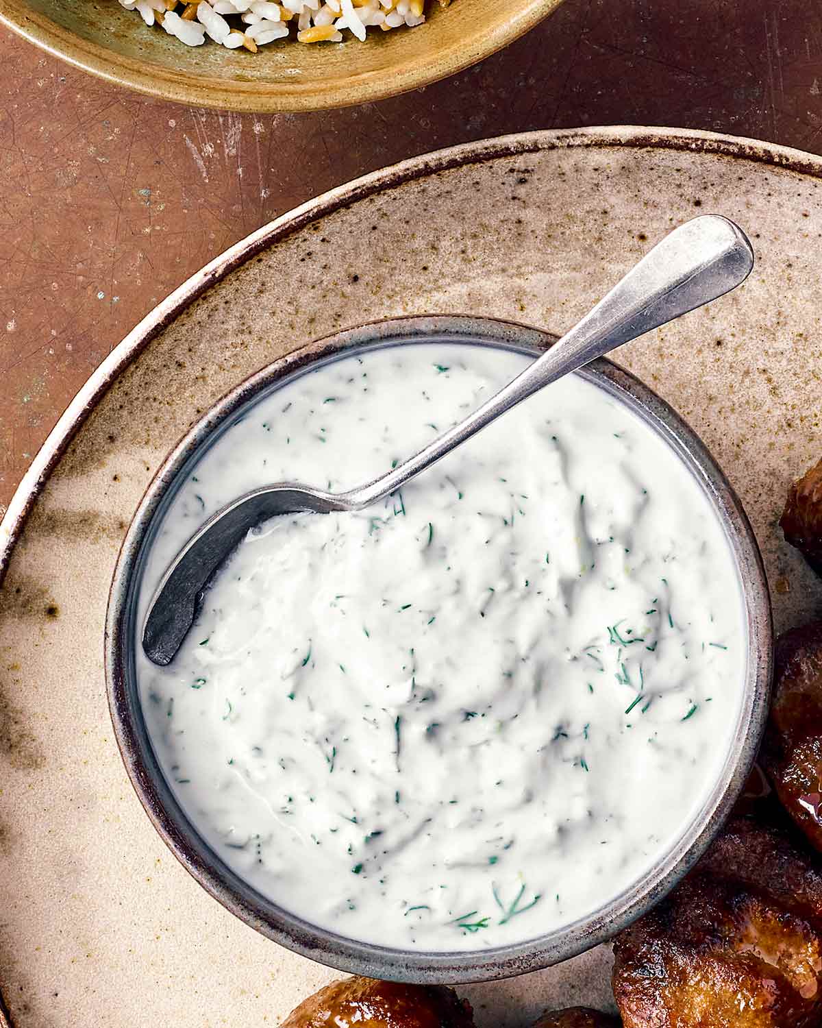 A bowl of preserved lemon yogurt sauce with a spoon resting in it.