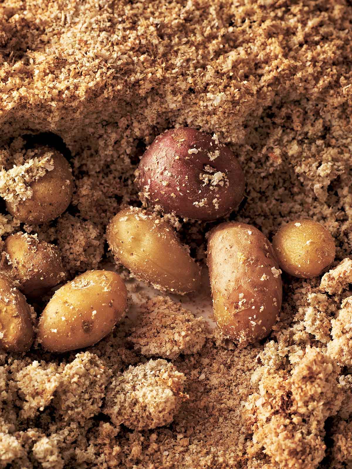 Several small salt-roasted potatoes surrounded by a bed of browned salt.