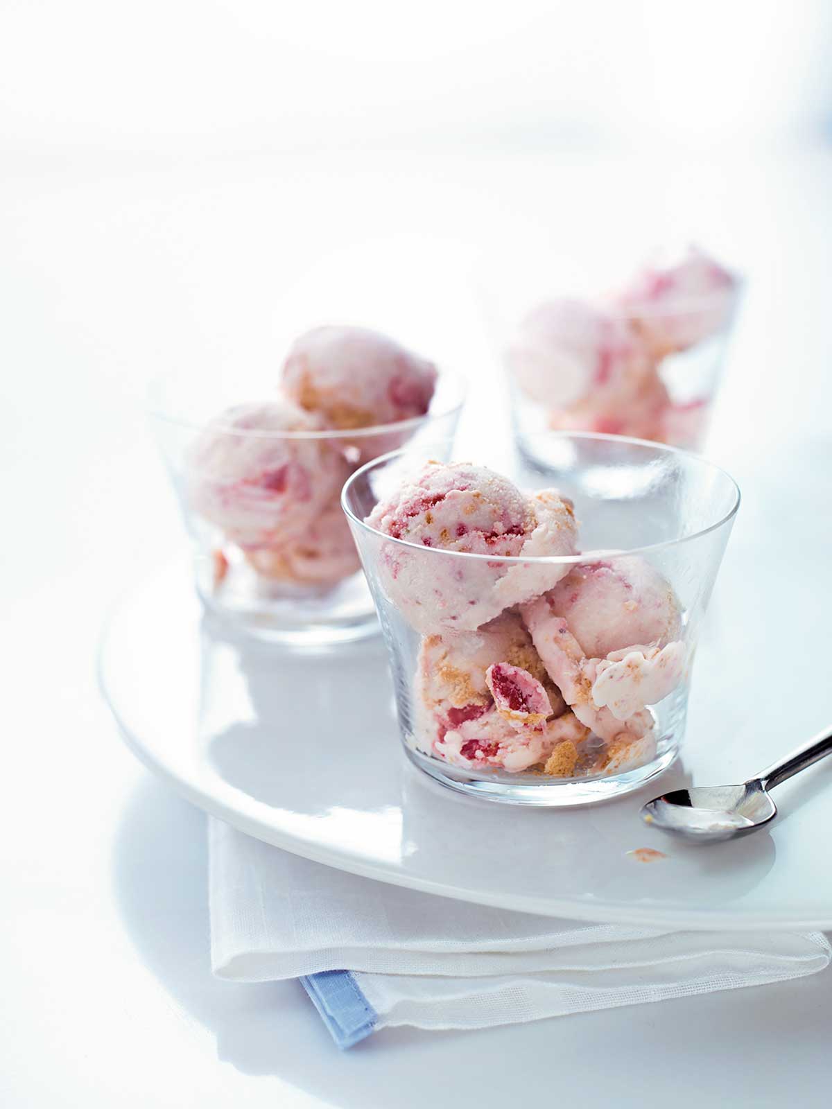 Three glass bowls filled with scoops of strawberry cheesecake ice cream.