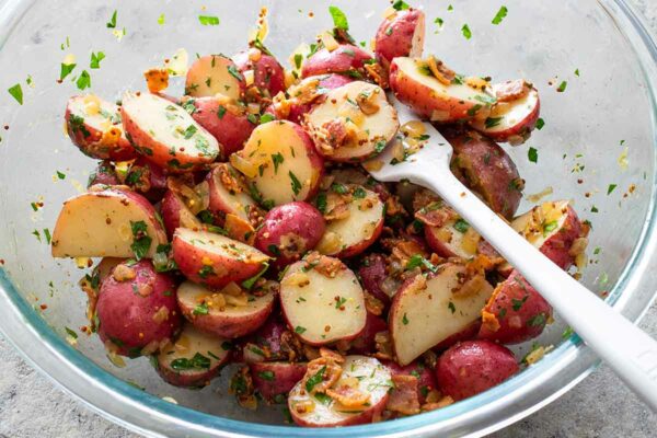 A bowl of German-style potato salad with a fork resting in it.