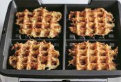 Four of Ina Garten's waffle iron hash browns in a waffle iron with the lid open.