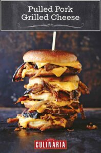 Three pulled pork grilled cheese sandwiches stacked on top of each other and secured with a wooden skewer.