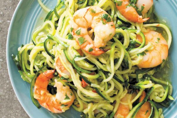 A blue plate topped with shrimp scampi with zucchini noodles.