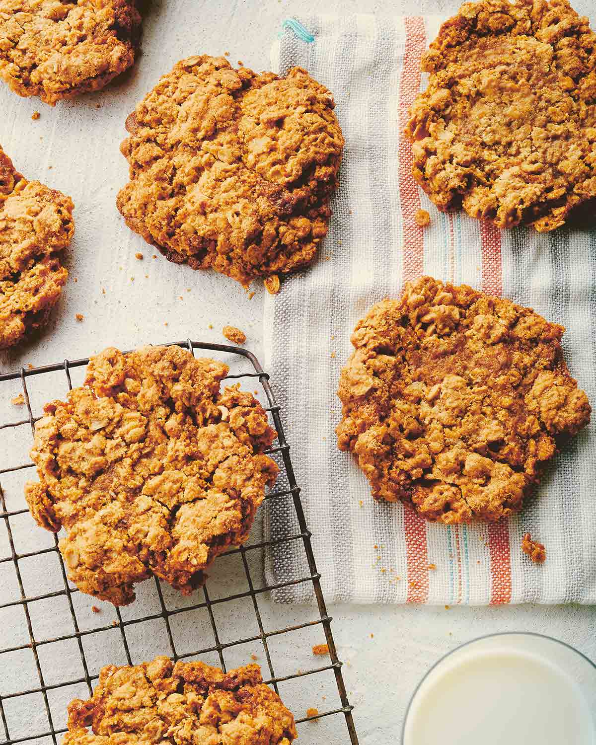 Seven vanilla bean oatmeal cookies scattered across a cooling rack and kitchen towel.