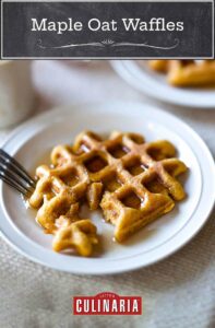 A maple oat waffles lying on a white plate with a fork and syrup in all the pockets.
