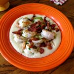 A Fiesta bowl filled with cheesy shrimp and grits with bacon