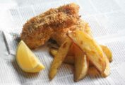2 pieces of panko coated fish with chips and a slice of lemon, laying of a sheet of newspaper