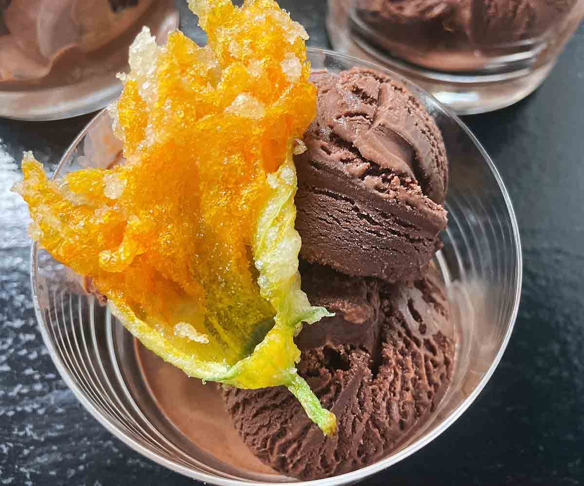 3 bowls of dark chocolate gelato, the one in the forefront is garnished with a tempura fried zucchini blossom.