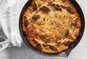 A beef bourguignon skillet pie in a cast-iron dish garnished with parsley and flaky sea salt.