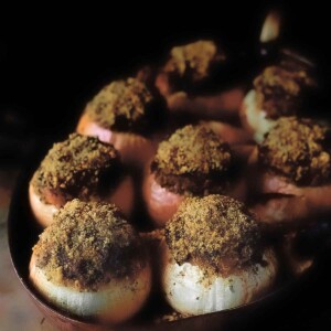 Roasted onions stuffed with ground lamb and apricots in a copper roasting pan.