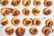 Fig jam thumbprint cookies in rows on a sheet of parchment paper.