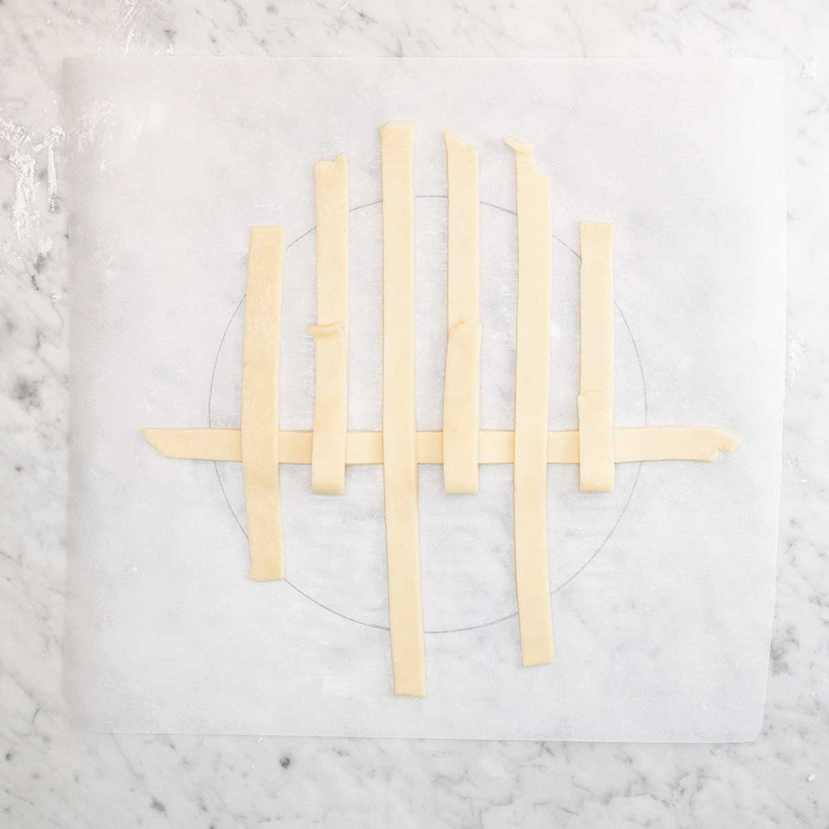 Strips of dough being arranged into a lattice pie crust.
