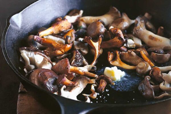 Pan-roasted mushrooms and a knob of butter melting in the center, in a cast-iron skillet.