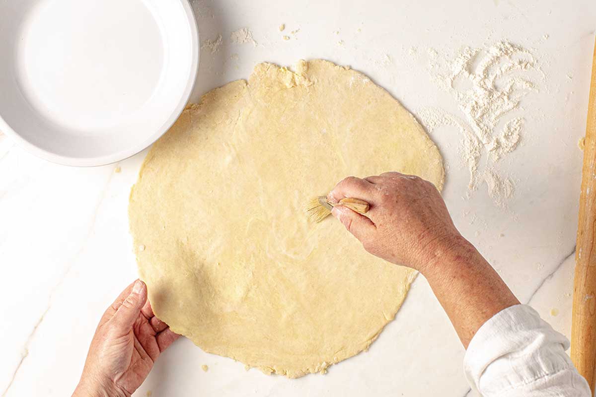A person brushing a pie crust.