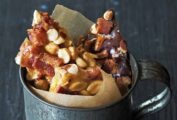 Bacon peanut brittle in shards, in a mug lined with parchment paper.